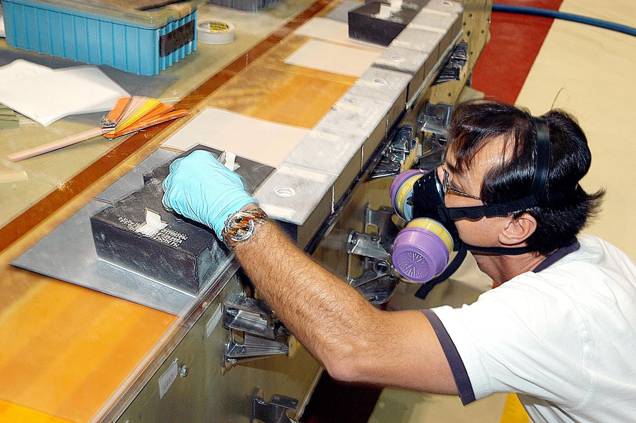 KENNEDY SPACE CENTER, FLA. -- In the Orbiter Processing Facility (OPF), United Space Alliance (USA) technician Mark Jetton  installs Thermal Protection System (TPS) tile on a simulated orbiter wing.   The wing, along with sections of Space Shuttle orbiter Enterprise (OV-101), will be transferred to the Southwest Research Institute for testing after the tile installation is complete. The testing has been requested by the Columbia Accident Investigation Board. For this initiative, sections of Enterprise were borrowed from the Smithsonian Institution's Air and Space Museum where the orbiter is being stored at the Washington Dulles International Airport. Enterprise was the first orbiter built in the Shuttle fleet and was used to conduct the Approach and Landing Test Program before the first powered Shuttle flight.