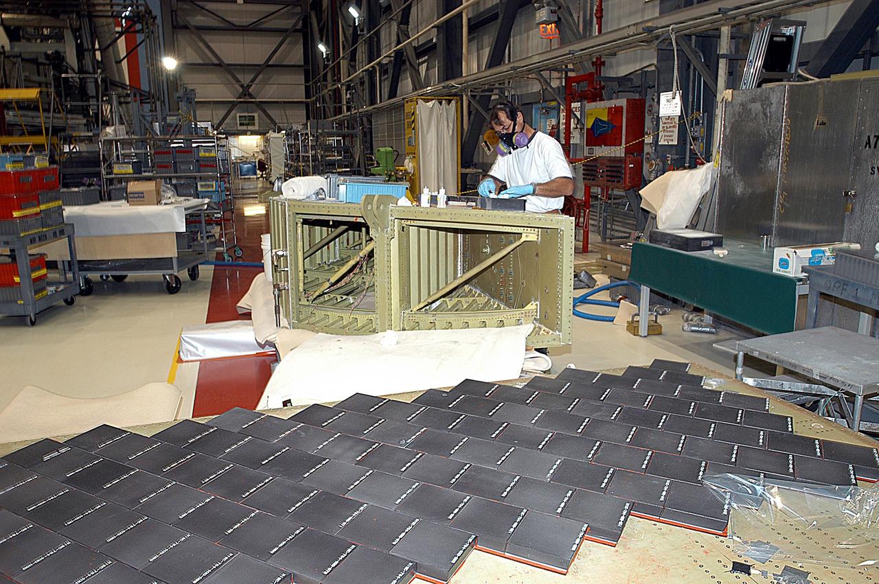 KENNEDY SPACE CENTER, FLA. -- In the Orbiter Processing Facility (OPF), United Space Alliance (USA) technician Mark Jetton installs Thermal Protection System (TPS) tile on a simulated orbiter wing.   The wing, along with sections of Space Shuttle orbiter Enterprise (OV-101), will be transferred to the Southwest Research Institute for testing after the tile installation is complete. The testing has been requested by the Columbia Accident Investigation Board. For this initiative, sections of Enterprise were borrowed from the Smithsonian Institution's Air and Space Museum where the orbiter is being stored at the Washington Dulles International Airport. Enterprise was the first orbiter built in the Shuttle fleet and was used to conduct the Approach and Landing Test Program before the first powered Shuttle flight.