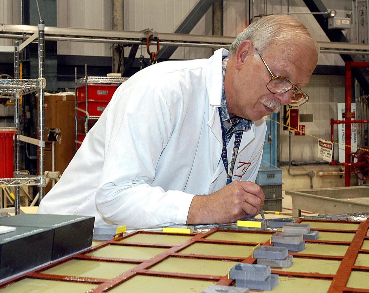 KENNEDY SPACE CENTER, FLA. -- In the Orbiter Processing Facility (OPF), Paul King, an employee of The Boeing Co., Huntington Beach, Calif., installs a strain gauge on a simulated orbiter wing in preparation for Thermal Protection System (TPS) tile installation.  The wing, along with sections of Space Shuttle orbiter Enterprise (OV-101), will be transferred to the Southwest Research Institute for testing after the tile installation is complete. The testing has been requested by the Columbia Accident Investigation Board. For this initiative, sections of Enterprise were borrowed from the Smithsonian Institution's Air and Space Museum where the orbiter is being stored at the Washington Dulles International Airport. Enterprise was the first orbiter built in the Shuttle fleet and was used to conduct the Approach and Landing Test Program before the first powered Shuttle flight.