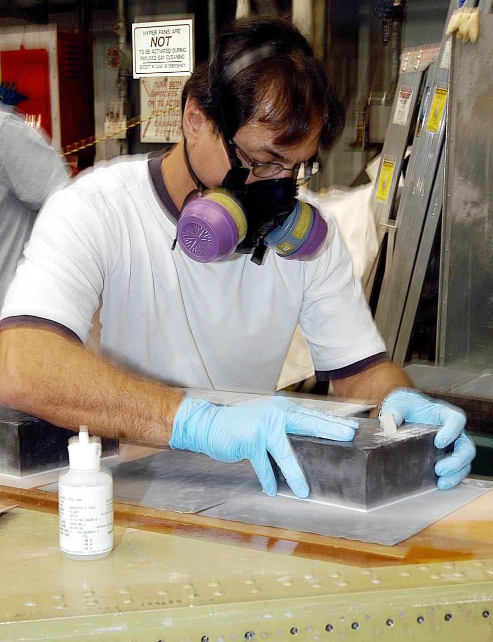 KENNEDY SPACE CENTER, FLA. -- In the Orbiter Processing Facility (OPF), United Space Alliance (USA) technician Mark Jetton installs Thermal Protection System (TPS) tile on a simulated orbiter wing.   The wing, along with sections of Space Shuttle orbiter Enterprise (OV-101), will be transferred to the Southwest Research Institute for testing after the tile installation is complete. The testing has been requested by the Columbia Accident Investigation Board. For this initiative, sections of Enterprise were borrowed from the Smithsonian Institution's Air and Space Museum where the orbiter is being stored at the Washington Dulles International Airport. Enterprise was the first orbiter built in the Shuttle fleet and was used to conduct the Approach and Landing Test Program before the first powered Shuttle flight.