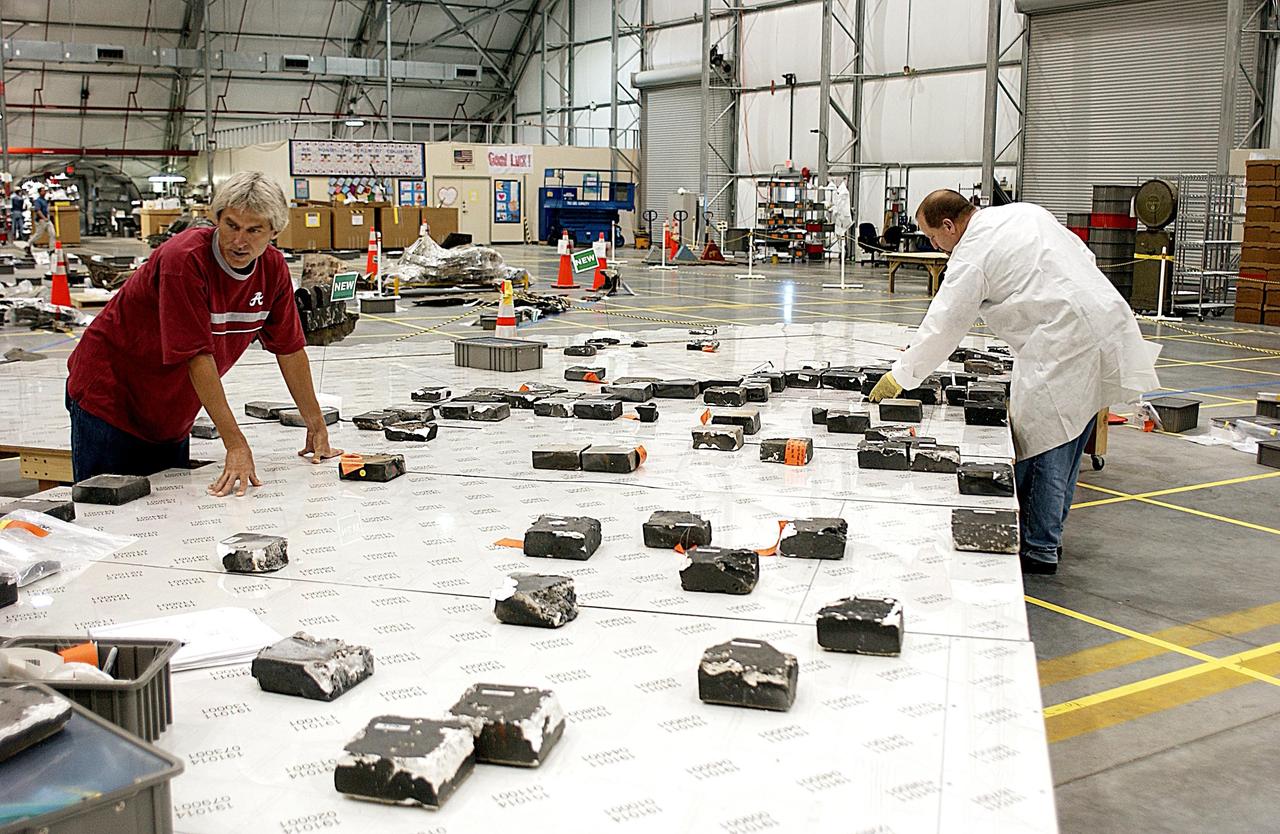 KENNEDY SPACE CENTER, FLA. --  In the RLV Hangar, members of the Columbia Reconstruction Project team place recovered Thermal Protection System (TPS) tile on a tabletop mock-up of the wing of Columbia. Shipped from Barksdale Air Force Base, Shreveport, La., more than 70,000 items, weighing 78,000 pounds, about 36 percent of the Shuttle by weight, have been delivered to KSC for use in the mishap investigation. Ground teams have completed 78 percent of their primary search area, and airborne crews finished 80 percent of their assigned area. Search teams have completed 98 percent of the underwater searches in Lake Nacogdoches and Toledo Bend Reservoir.