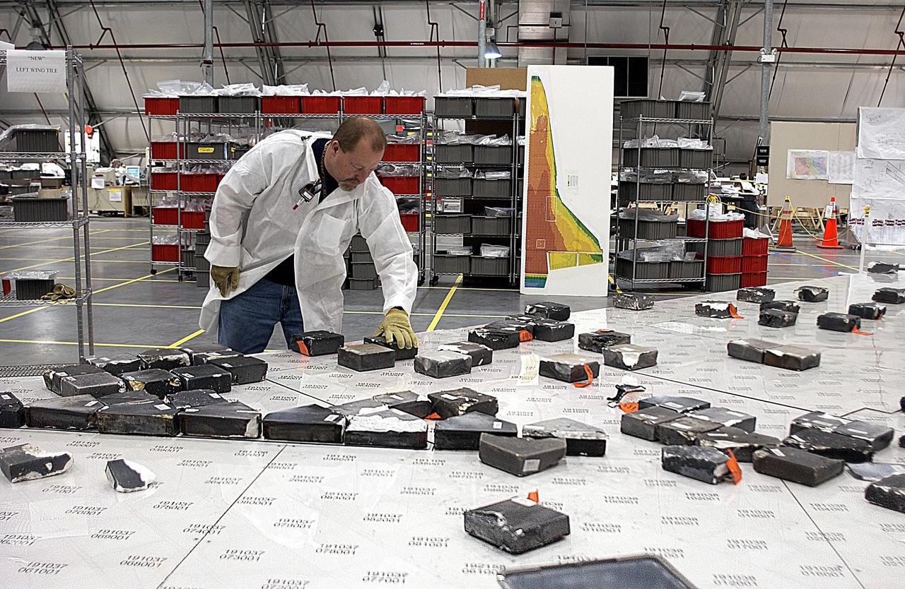 KENNEDY SPACE CENTER, FLA. --  In the RLV Hangar, a member of the Columbia Reconstruction Project team places recovered Thermal Protection System (TPS) tile on a tabletop mock-up of the wing of Columbia. Shipped from Barksdale Air Force Base, Shreveport, La., more than 70,000 items, weighing 78,000 pounds, about 36 percent of the Shuttle by weight, have been delivered to KSC for use in the mishap investigation. Ground teams have completed 78 percent of their primary search area, and airborne crews finished 80 percent of their assigned area. Search teams have completed 98 percent of the underwater searches in Lake Nacogdoches and Toledo Bend Reservoir.