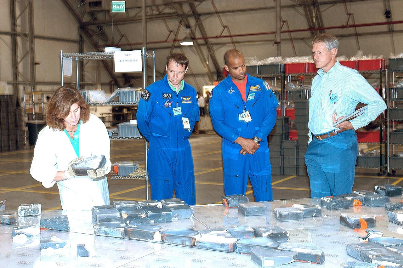 KENNEDY SPACE CENTER, FLA. -- In the RLV Hangar, two members of the STS-116 crew look at pieces of tile from Columbia. Center left is Mission Specialist Christer Fuglesang, with the European Space Agency, and center right is Mission Specialist Robert Curbeam. The Columbia Reconstruction Project Team is examining and identifying pieces as they are delivered to the hangar. More than 70,000 items, weighing 78,000 pounds, about 36 percent of the Shuttle by weight, have been delivered to KSC for use in the mishap investigation.
