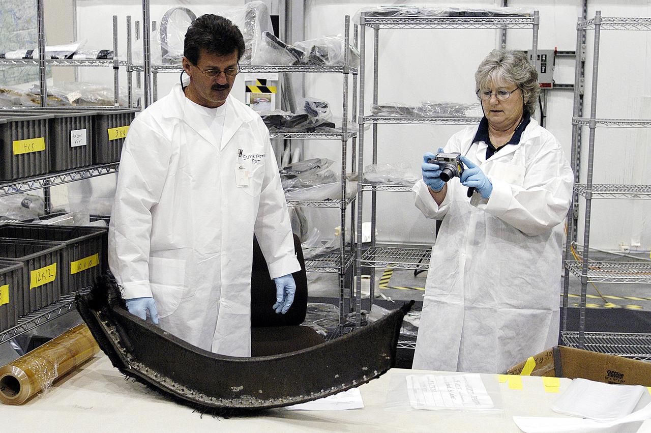 KENNEDY SPACE CENTER, FLA. --  In the RLV Hangar, members of the Columbia Reconstruction Project Team prepare to photograph a piece of debris from Columbia. The team is examining and identifying pieces as they are delivered to the hangar.  More than 70,000 items, weighing 78,000  pounds, about 36 percent of the Shuttle by weight, have been  delivered to KSC for use in the mishap  investigation.
