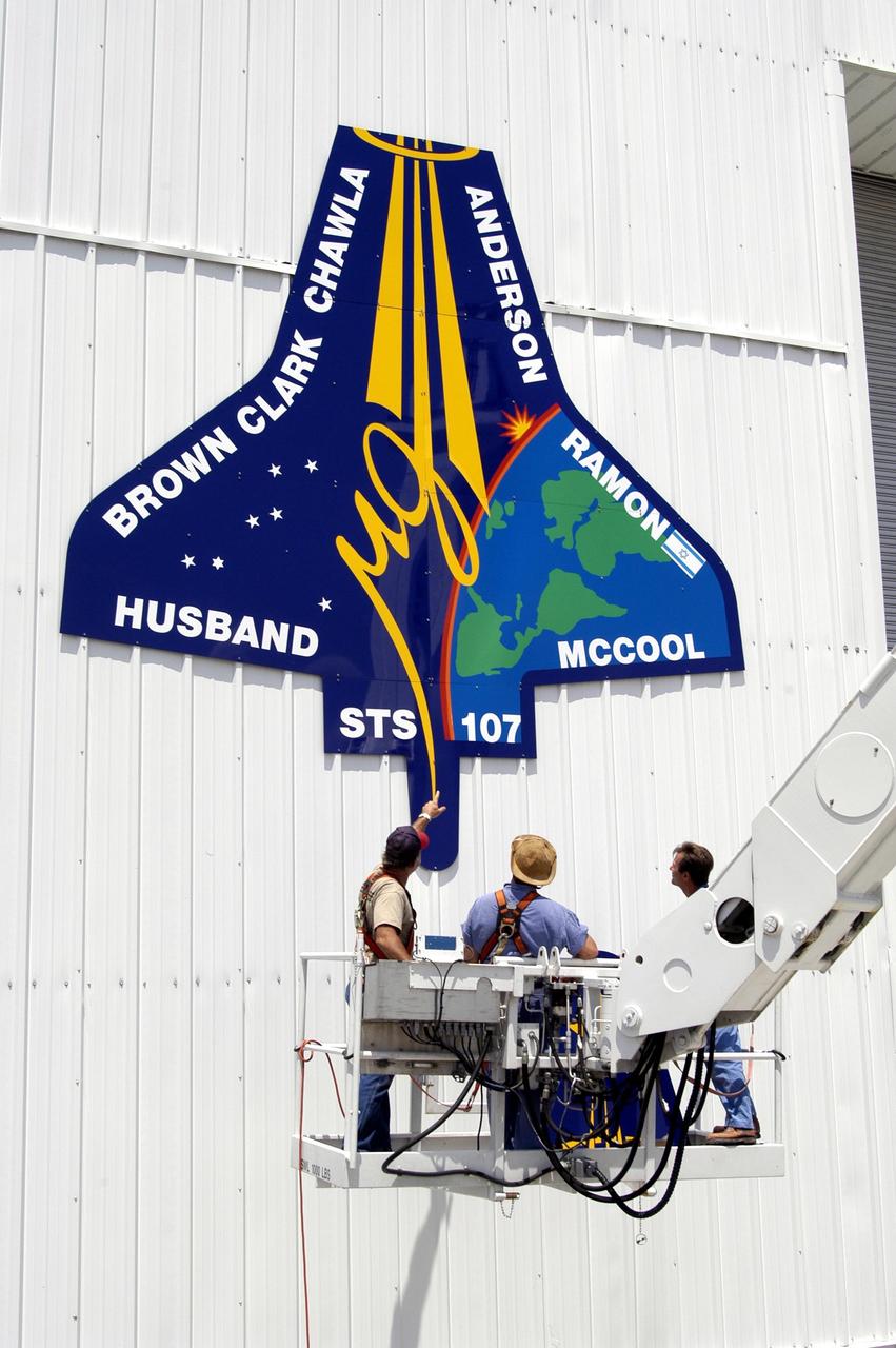 KENNEDY SPACE CENTER, FLA. - Workers are placing the mission patch for STS-107 on the outside of the RLV Hangar at KSC.  The hangar is the site of the Columbia Reconstruction Project, where pieces of debris from Columbia are being collected and identified as part of the mishap investigation.
