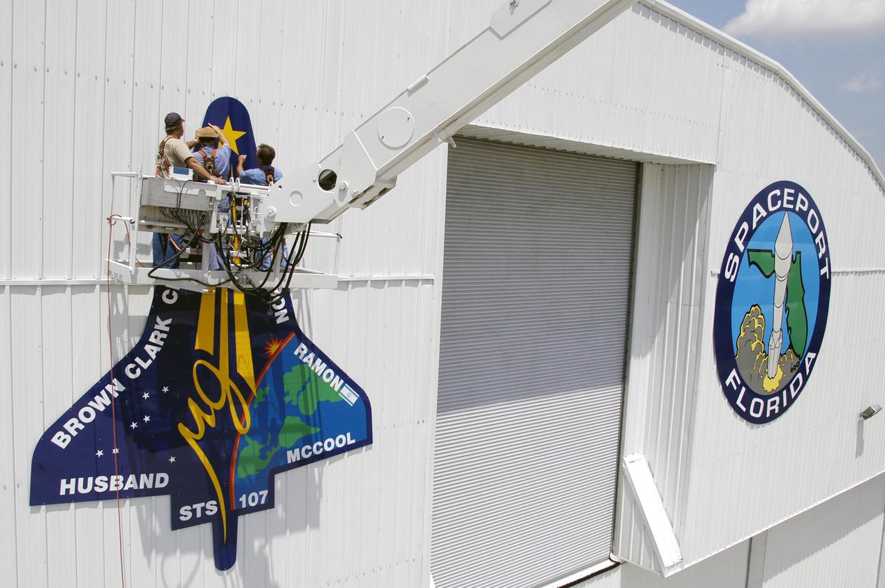 KENNEDY SPACE CENTER, FLA. - Workers place the final piece of the mission patch for STS-107 on the outside of the RLV Hangar at KSC.  The hangar is the site of the Columbia Reconstruction Project, where pieces of debris from Columbia are being collected and identified as part of the mishap investigation.