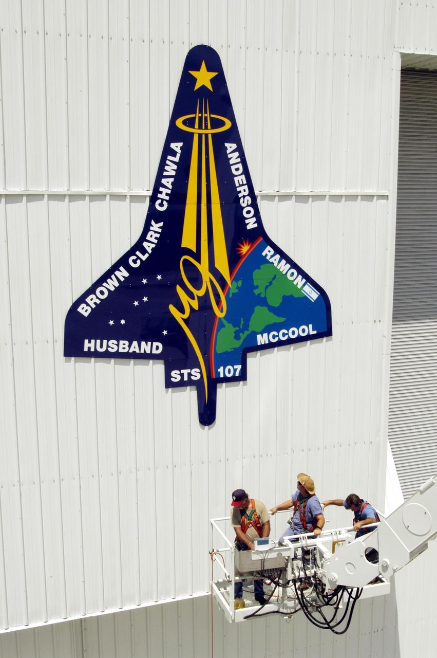 KENNEDY SPACE CENTER, FLA. - Workers lower their bucket after placing the final piece of the mission patch for STS-107 on the outside of the RLV Hangar at KSC.  The hangar is the site of the Columbia Reconstruction Project, where pieces of debris from Columbia are being collected and identified as part of the mishap investigation.