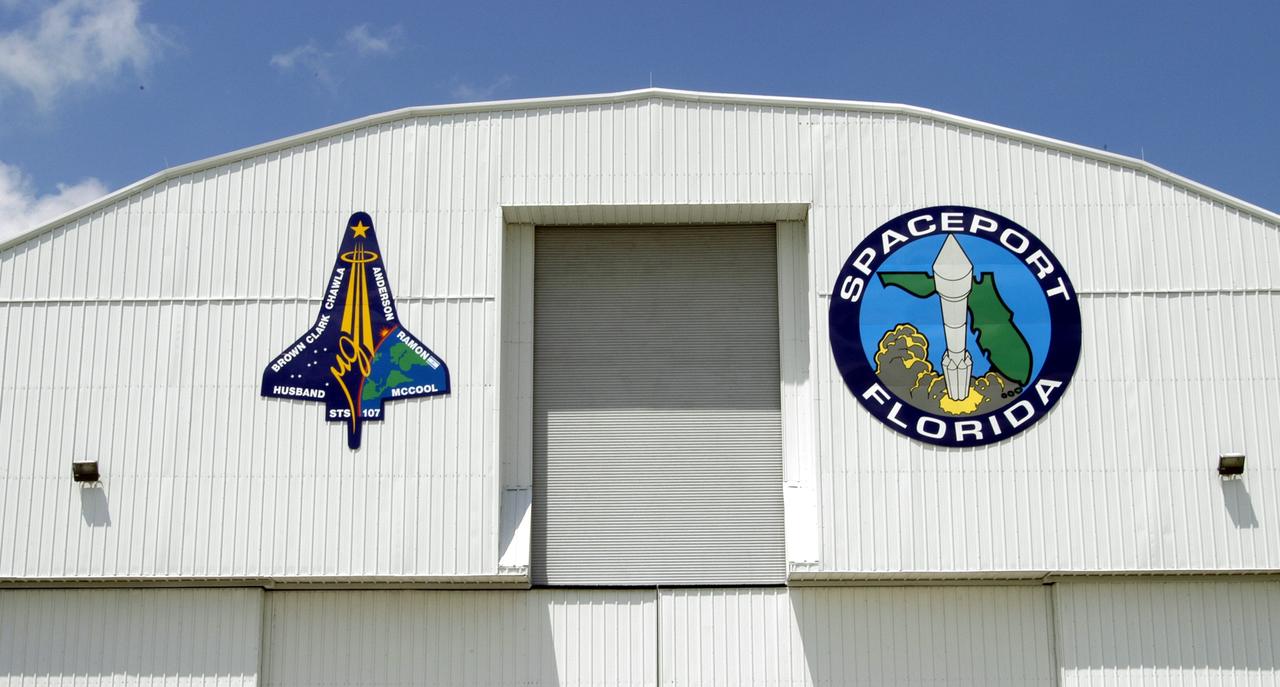 KENNEDY SPACE CENTER, FLA. - The mission patch for STS-107 is displayed, left, on the outside of the RLV Hangar at KSC. The hangar is the site of the Columbia Reconstruction Project, where pieces of debris from Columbia are being collected and identified as part of the mishap investigation.