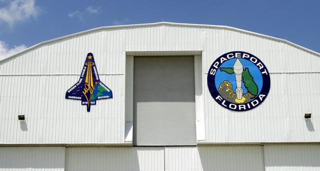 KENNEDY SPACE CENTER, FLA. - The mission patch for STS-107 is displayed, left, on the outside of the RLV Hangar at KSC. The hangar is the site of the Columbia Reconstruction Project, where pieces of debris from Columbia are being collected and identified as part of the mishap investigation.