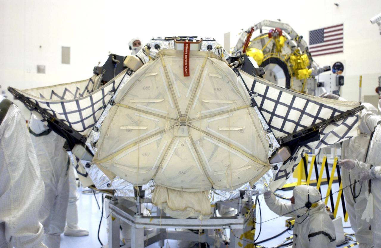 KENNEDY SPACE CENTER, FLA. - Workers check different areas of the lander as the petals close in around the Mars Exploration Rover 2 (MER-A).  The lander and rover will subsequently be enclosed within an aeroshell for launch.  The MER Mission consists of two identical rovers designed to cover roughly 110 yards each Martian day over various terrain. Each rover will carry five scientific instruments that will allow it to search for evidence of liquid water that may have been present in the planet's past.  Identical to each other, the rovers will land at different regions of Mars.  Launch date for this first of NASA's two Mars Exploration Rover missions is scheduled no earlier than June 6.