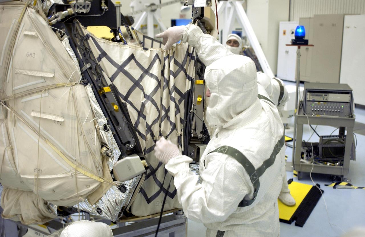 KENNEDY SPACE CENTER, FLA. - Kevin Burke, with the Jet Propulsion Laboratory, Pasadena, Calif., checks the closure of the lander petals and rover egress hardware around the Mars Exploration Rover 2 (MER-A). The lander and rover will subsequently be enclosed within an aeroshell for launch. The MER Mission consists of two identical rovers designed to cover roughly 110 yards each Martian day over various terrain. Each rover will carry five scientific instruments that will allow it to search for evidence of liquid water that may have been present in the planet's past. Identical to each other, the rovers will land at different regions of Mars. Launch date for this first of NASA's two Mars Exploration Rover missions is scheduled no earlier than June 6.