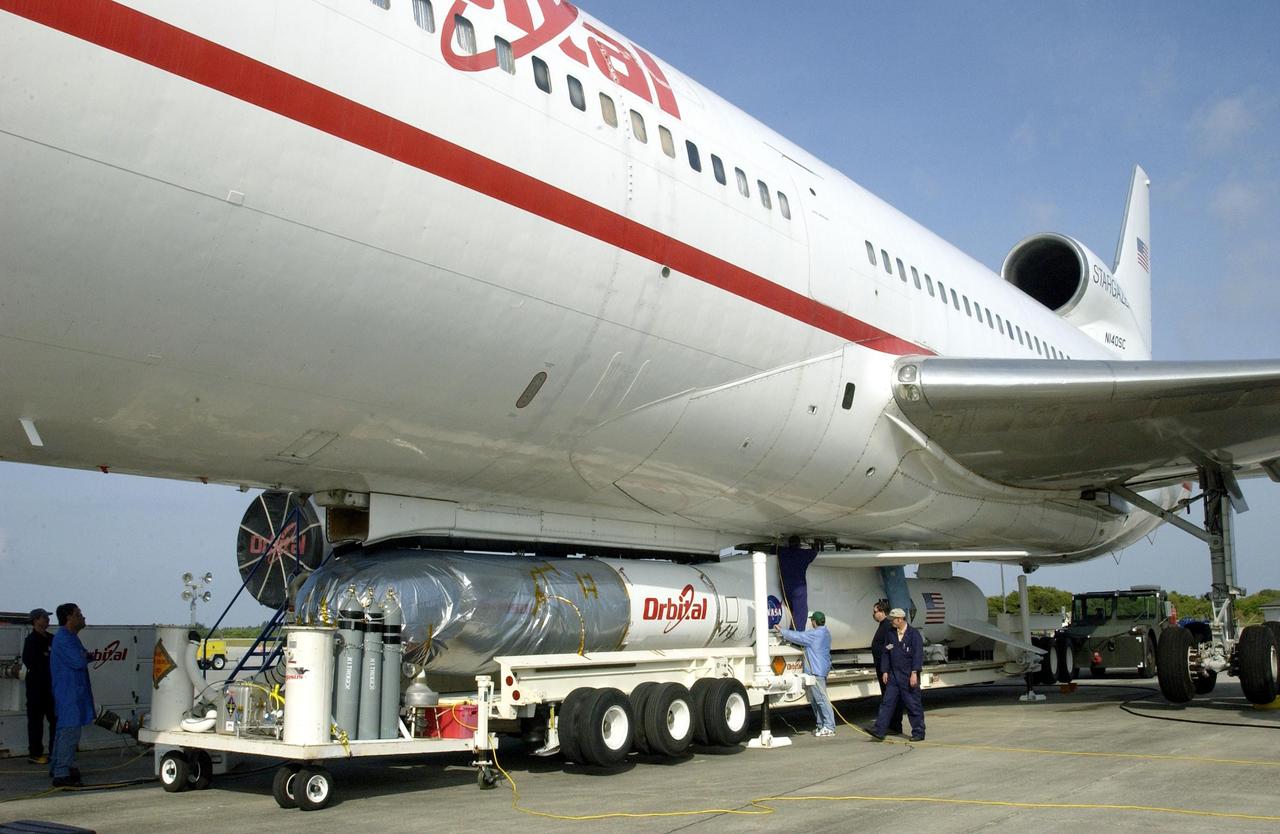 KENNEDY SPACE CENTER, FLA. - At Cape Canaveral Air Force Station, workers finish attaching the mated Pegasus XL and Galaxy Evolution Explorer (GALEX) satellite to the Orbital Sciences L-1011 aircraft.  The GALEX, to be launched April 28 from the L-1011, will carry into space an orbiting telescope that will observe a million galaxies across 10 billion years of cosmic history to help astronomers determine when the stars and elements we see today had their origins. The spacecraft will sweep the skies for 28 months using state-of-the-art ultraviolet detectors to single out galaxies dominated by young, hot, short-lived stars that give off a great deal of energy at that wavelength.  These galaxies are actively creating stars, and therefore provide a window into the history and causes of star formation in galaxies.