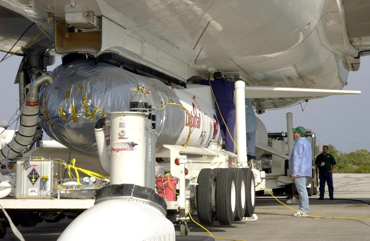 KENNEDY SPACE CENTER, FLA. - At Cape Canaveral Air Force Station, workers finish attaching the mated Pegasus XL and Galaxy Evolution Explorer (GALEX) satellite to the Orbital Sciences L-1011 aircraft.  The GALEX, to be launched April 28 from the L-1011, will carry into space an orbiting telescope that will observe a million galaxies across 10 billion years of cosmic history to help astronomers determine when the stars and elements we see today had their origins. The spacecraft will sweep the skies for 28 months using state-of-the-art ultraviolet detectors to single out galaxies dominated by young, hot, short-lived stars that give off a great deal of energy at that wavelength.  These galaxies are actively creating stars, and therefore provide a window into the history and causes of star formation in galaxies.