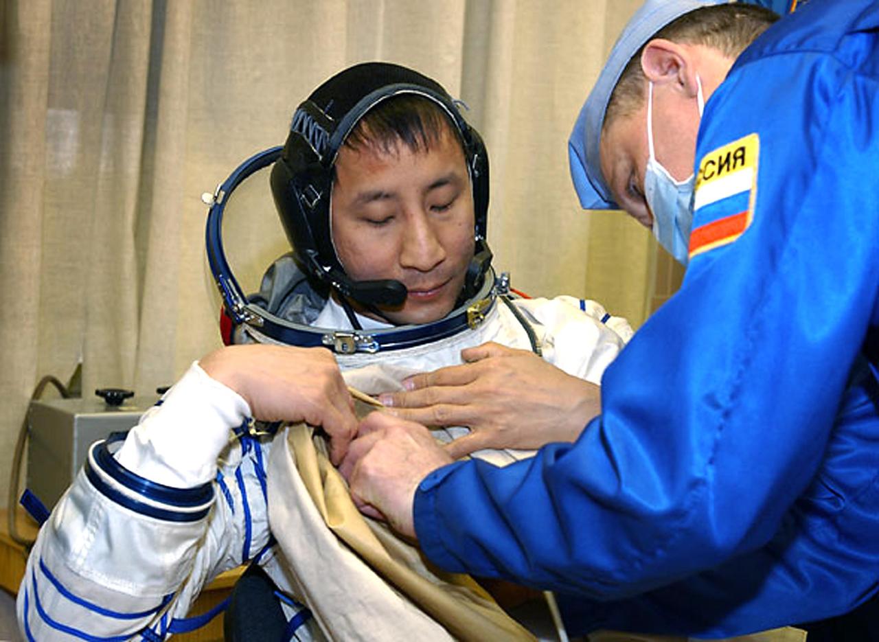 Baikonur Cosmodrome, Kazakhstan. Building 254, Soyuz Integration Facility.  Astronaut Edward T. Lu, NASA ISS science officer and flight engineer for Expedition Seven, dons his Russian Sokol suit for the leak check and Soyuz inspection, seat liner check.  Veteran Russian cosmonaut Yuri Malenchenko and veteran NASA astronaut Ed Lu have been named as the primary crew for the planned April 26, 2003, launch of a Russian Soyuz TMA-2 spacecraft to the International Space Station. Malenchenko and Lu will be called the Expedition 7 crew. Russian cosmonaut Alexander Kaleri and NASA astronaut Michael Foale are the backup crewmembers to Malenchenko and Lu.  Expedition 6 Commander Ken Bowersox, Flight Engineer Nikolai Budarin and NASA Space Station Science Officer Don Pettit will return to Earth aboard the Soyuz TMA-1 craft in May 2003. The three Expedition 6 crewmembers were launched on Nov. 23, 2002. They have been aboard the Station since November 25. They were originally scheduled to return in March aboard the Space Shuttle Atlantis during the STS-114 mission.  Malenchenko and Lu will continue to operate the science payloads already on board, as well as maintaining the Station.  Photo Credit: NASA/Bill Ingalls