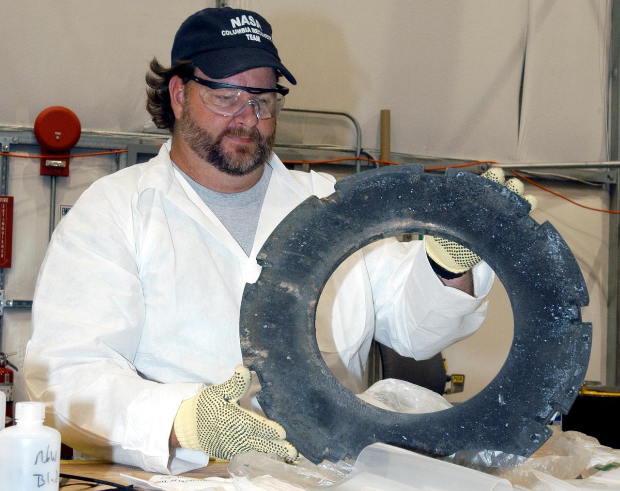 KENNEDY SPACE CENTER, FLA. - In the RLV Hangar, a member of the Columbia Reconstruction Project Team tries to identify a piece of debris from Columbia.  More than 70,000 items have been delivered to KSC for use in the mishap investigation.