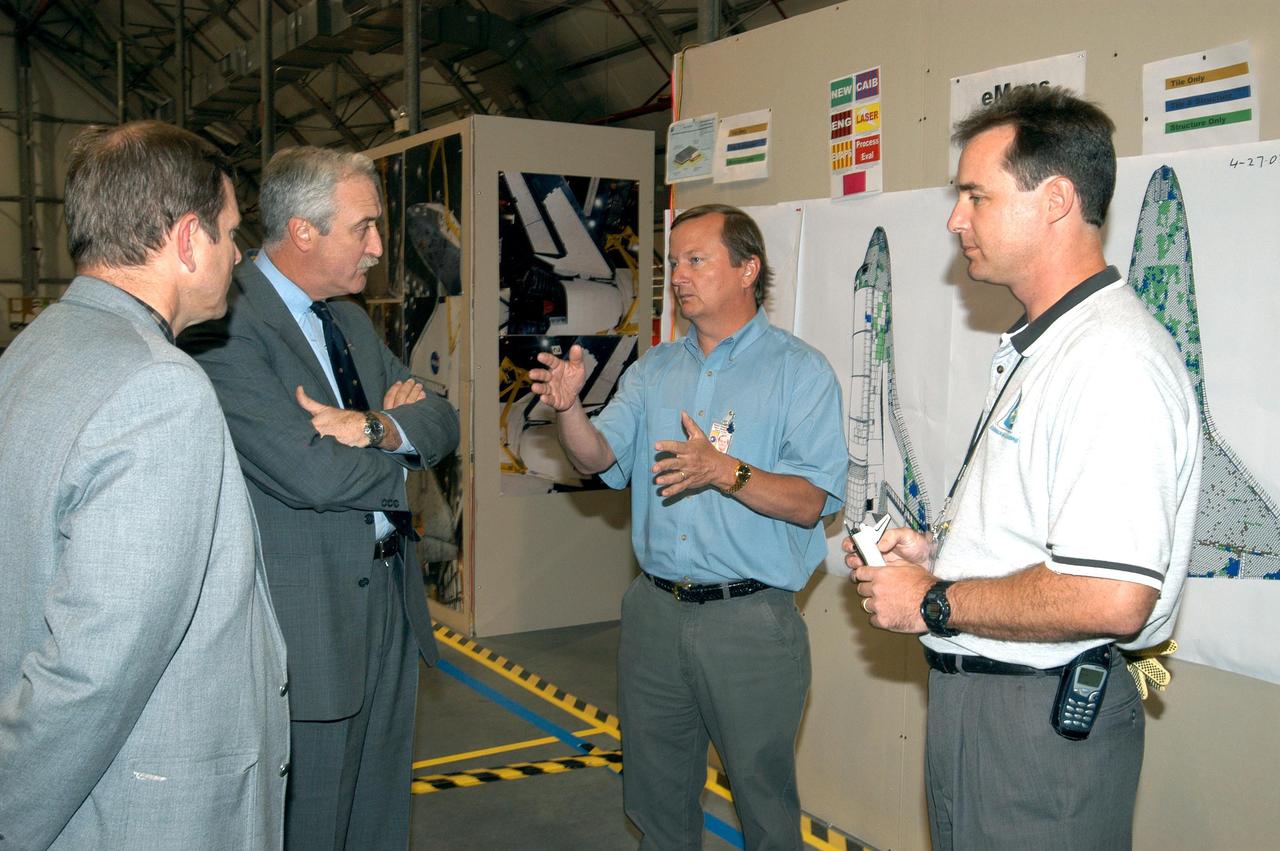 KENNEDY SPACE CENTER, FLA. - In the RLV Hangar, NASA Administrator Sean O'Keefe (second from left) listens as Shuttle Launch Director Mike Leinbach (center) explains an aspect of the investigation into the Space Shuttle Columbia accident.  On the right is Shuttle Test Director Steve Altemus, a member of the Columbia Reconstruction Project Team. To date, more than 70,000 items have been delivered to KSC for use in the ongoing mishap investigation.