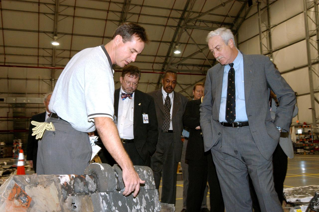 KENNEDY SPACE CENTER, FLA. - In the RLV Hangar, Shuttle Test Director Steve Altemus (left), a member of the Columbia Reconstruction Project Team, discusses a piece of debris from the Space Shuttle Columbia with NASA Administrator Sean O'Keefe (right). To date, more than 70,000 items have been delivered to KSC for use in the ongoing mishap investigation.