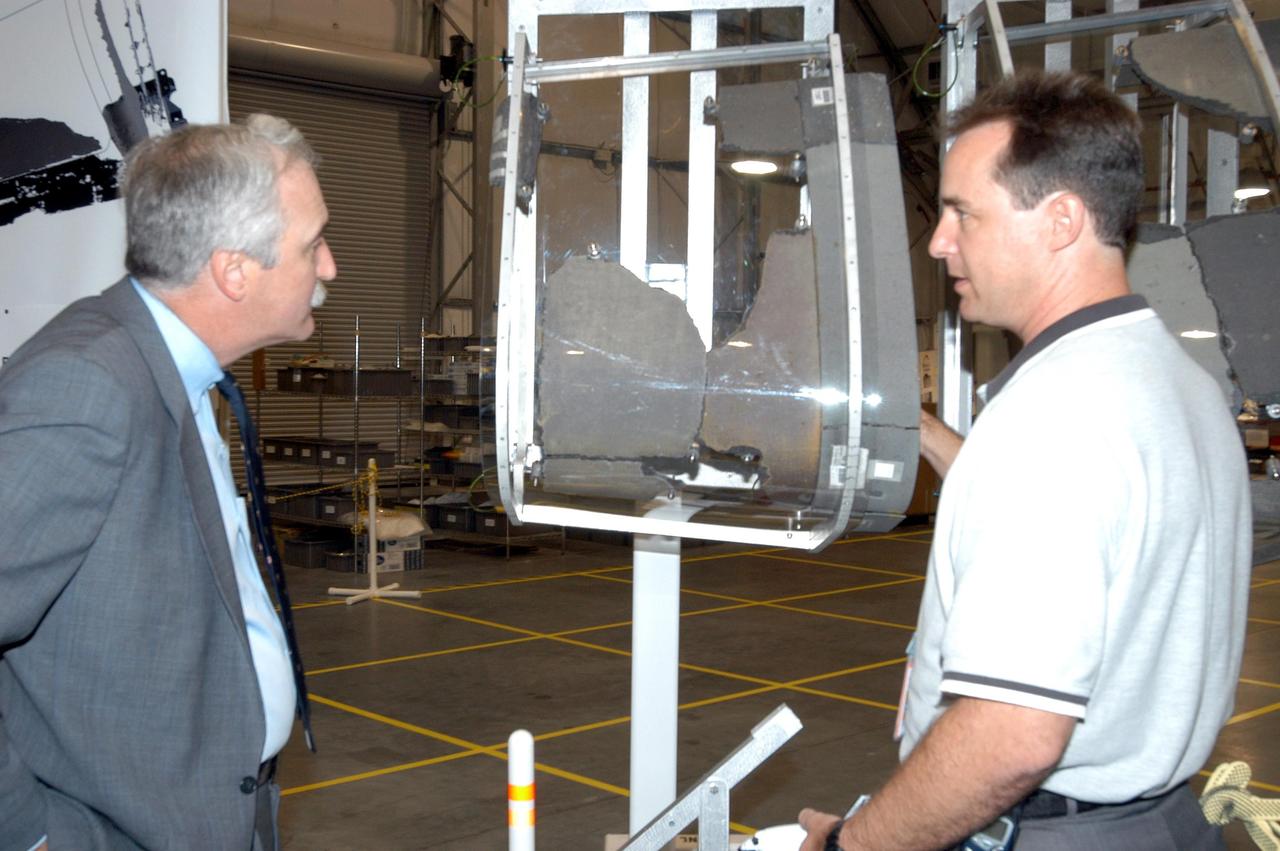 KENNEDY SPACE CENTER, FLA. - In the RLV Hangar, Shuttle Test Director Steve Altemus (right), a member of the Columbia Reconstruction Project Team, explains the fixture which holds the leading edge panels recovered from the left wing of Space Shuttle Columbia to NASA Administrator Sean O'Keefe (left). To date, more than 70,000 items have been delivered to KSC for use in the ongoing mishap investigation.