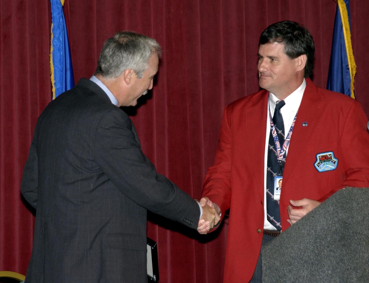 KENNEDY SPACE CENTER, FLA. - NASA Administrator Sean O'Keefe shakes hands with Kevin Hoshstrasser after presenting him with a framed photograph. Hoshstrasser is chairman of the 40th Space Congress held April 28-May 1, 2003, in Cape Canaveral, Fla. The international conference gathers attendees from the scientific community, the space industry workforce, educators and local supporting industries. This year's event commemorated the 40th anniversary of the Kennedy Space Center and the Centennial of Flight. The theme for the Space Congress was "Linking the Past to the Future: A Celebration of Space."
