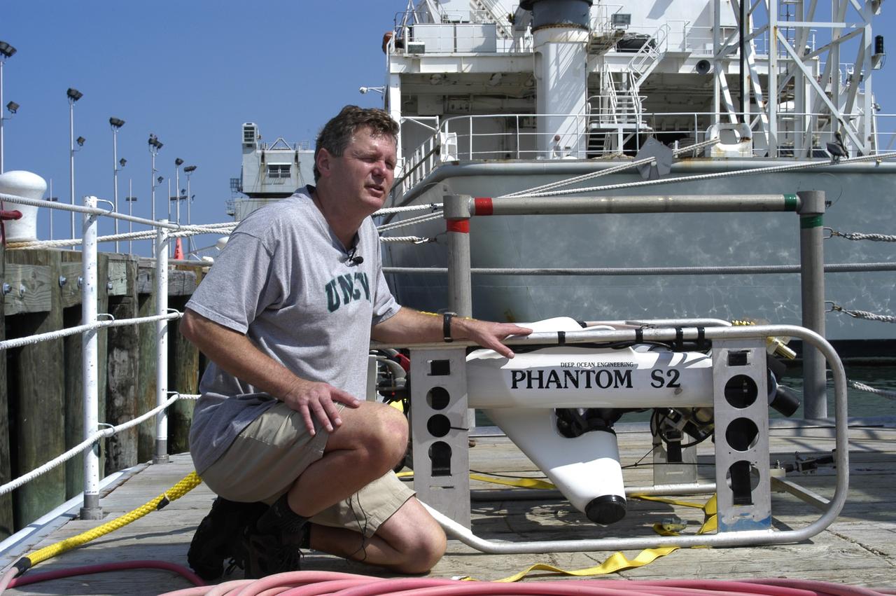 KENNEDY SPACE CENTER, FLA. -  Andrew Shepard, expedition leader, National Undersea Research Center, University of North Carolina at Wilmington, N. Car., poses on deck of the Liberty Star  with some of the equipment to be used in the Oculina Banks project.  The ship will be the site of an undersea expedition to characterize the condition of the deep-sea coral reefs and reef fish populations in the Oculina Banks, a marine protected area, 20 miles offshore of the east coast of Florida.  He and other scientists will be deploying an underwater robot, a seafloor sampler, and the Passive Acoustic Monitoring System (PAMS).  Dr. Grant Gilmore was co-principle investigator of the PAMS,  originally developed by NASA to monitor the impact of rocket launches on wildlife refuge lagoons at KSC.   The research is sponsored by NOAA Fisheries.  The ship departed from Port Canaveral April 29 and will return May 9.