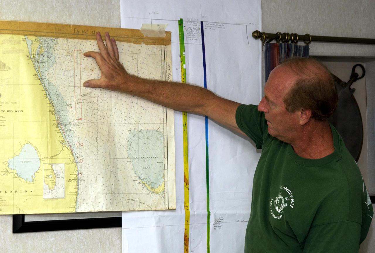 KENNEDY SPACE CENTER, FLA. - John Reed, co-principal investigator, Harbor Branch Oceanographic Institution, points to the Oculina Banks, a marine protected area, 20 miles offshore of the east coast of Florida.  A team of scientists will deploy an underwater robot, a seafloor sampler, and the Passive Acoustic Monitoring System (PAMS), on an undersea expedition to characterize the condition of the deep-sea coral reefs and reef fish populations in the Oculina Banks.  The PAMS was originally developed by NASA to monitor the impact of rocket launches on wildlife refuge lagoons at KSC.   The research is sponsored by NOAA Fisheries and will take place onboard the Liberty Star.  The ship departed from Port Canaveral April 29 and will return May 9.