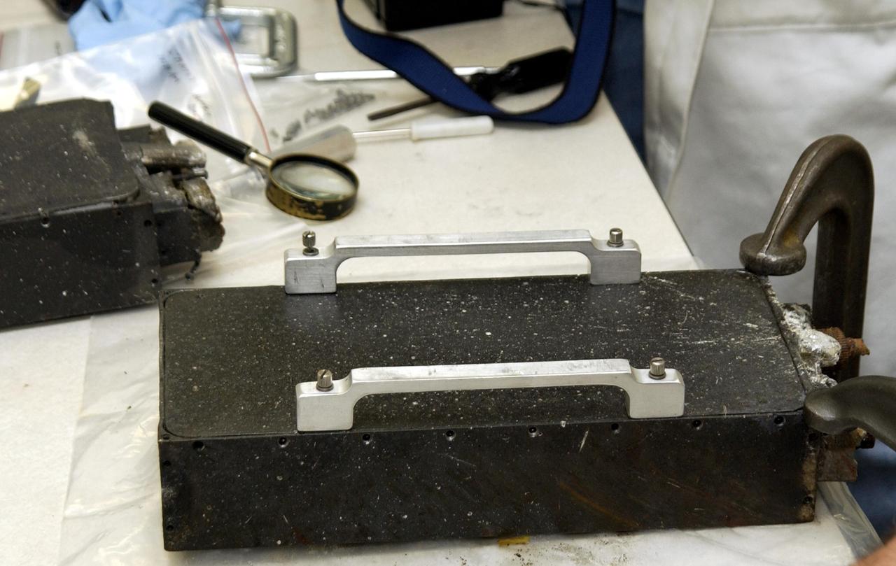 KENNEDY SPACE CENTER, FLA. - The Commercial ITA Biomedical Experiments payload retrieved from debris of Columbia is being dismantled at KSC.  Inside are several experiments carried on mission STS-107 that will be removed and transferred to alternate containers.  One experiment, the Growth of Bacterial Biofilm on Surfaces during Spaceflight (GOBBSS), was a Planetary Society-sponsored astrobiology experiment developed by the Israeli Aerospace Medical Institute and the Johnson Space Center Astrobiology Center, with joint participation of an Israeli and a Palestinian student.  The recovery team includes Eran Schenker of the Israeli Aerospace Medical Institute; David Warmflash of JSC, John Cassanto of ITA, and Louis Friedman, executive director of the Planetary Society.  The GOBBSS material will be sent to JSC where the science team will analyze the samples, studying the effects of spaceflight on bacterial growth.