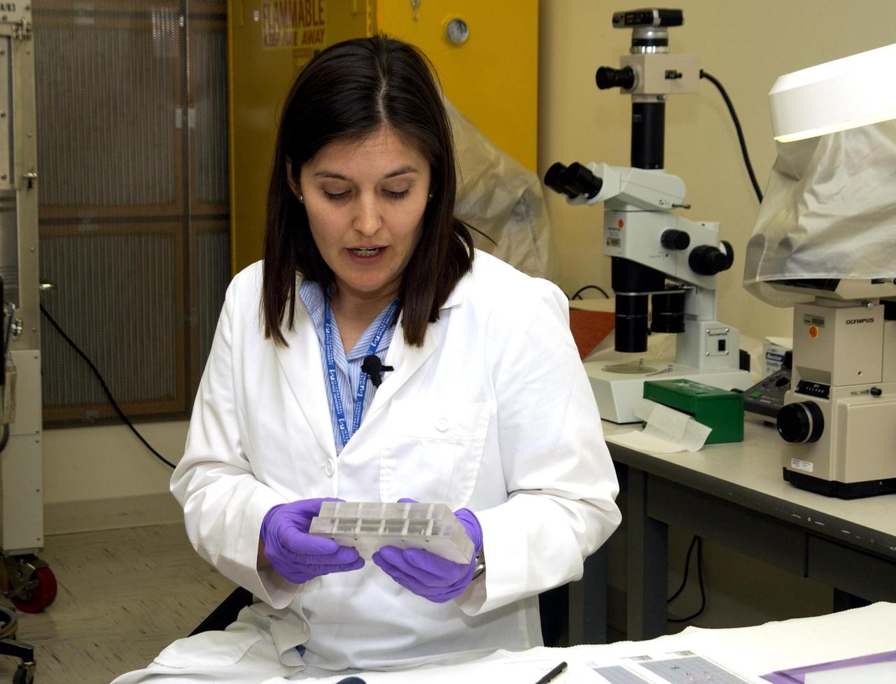 KENNEDY SPACE CENTER, FLA. -  Valerie Cassanto holds a piece of the Commercial ITA Biomedical Experiments payload that was carried on mission STS-107 and recently recovered.  She is the daughter of John Cassanto of ITA, who is part of a recovery team transferring experiments to alternate containers. One of the experiments was the Growth of Bacterial Biofilm on Surfaces during Spaceflight (GOBBSS), a Planetary Society-sponsored astrobiology experiment developed by the Israeli Aerospace Medical Institute and the Johnson Space Center Astrobiology Center, with joint participation of an Israeli and a Palestinian student.  The recovery team also includes Eran Schenker of the Israeli Aerospace Medical Institute; David Warmflash of JSC, and Louis Friedman, executive director of the Planetary Society.  The GOBBSS material will be sent to JSC where the science team will analyze the samples, studying the effects of spaceflight on bacterial growth.