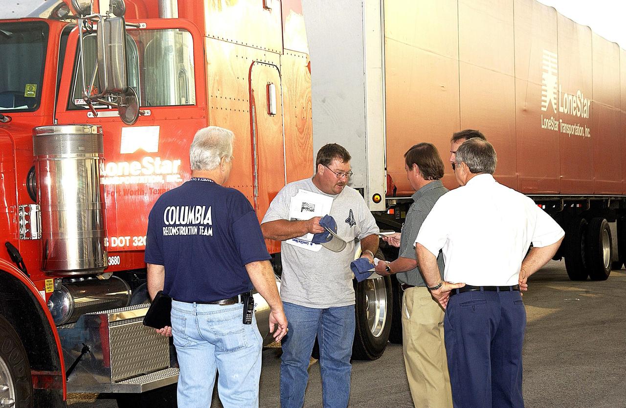 KENNEDY SPACE CENTER, FLA. - Shuttle Launch Director Mike Leinbach, third from left, greets the truck driver delivering the final shipment of Columbia debris.  The recovery efforts have been concluded in East Texas.  Prior to this final shipment, the total number of items at KSC is 82,567, weighing 84,800 pounds or 38 percent of the total dry weight of Columbia.  Of those items, 78,760 have been identified, with 753 placed on the left wing grid in the RLV Hangar.