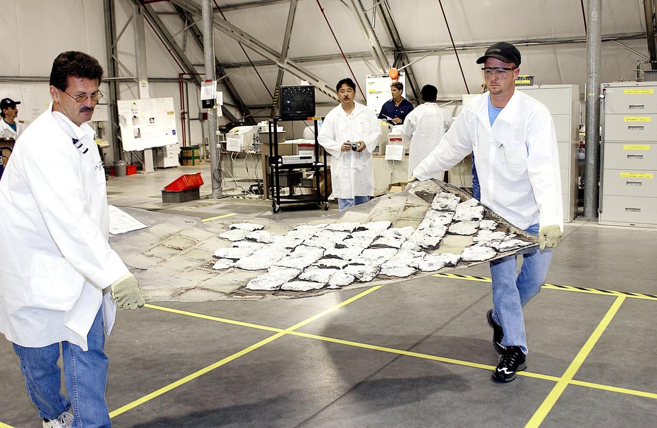 KENNEDY SPACE CENTER, FLA. - Members of the Columbia Reconstruction Project Team carry part of the final shipment of debris. The recovery efforts have been concluded in East Texas. Prior to this final shipment, the total number of items at KSC is 82,567, weighing 84,800 pounds or 38 percent of the total dry weight of Columbia. Of those items, 78,760 have been identified, with 753 placed on the left wing grid in the RLV Hangar.