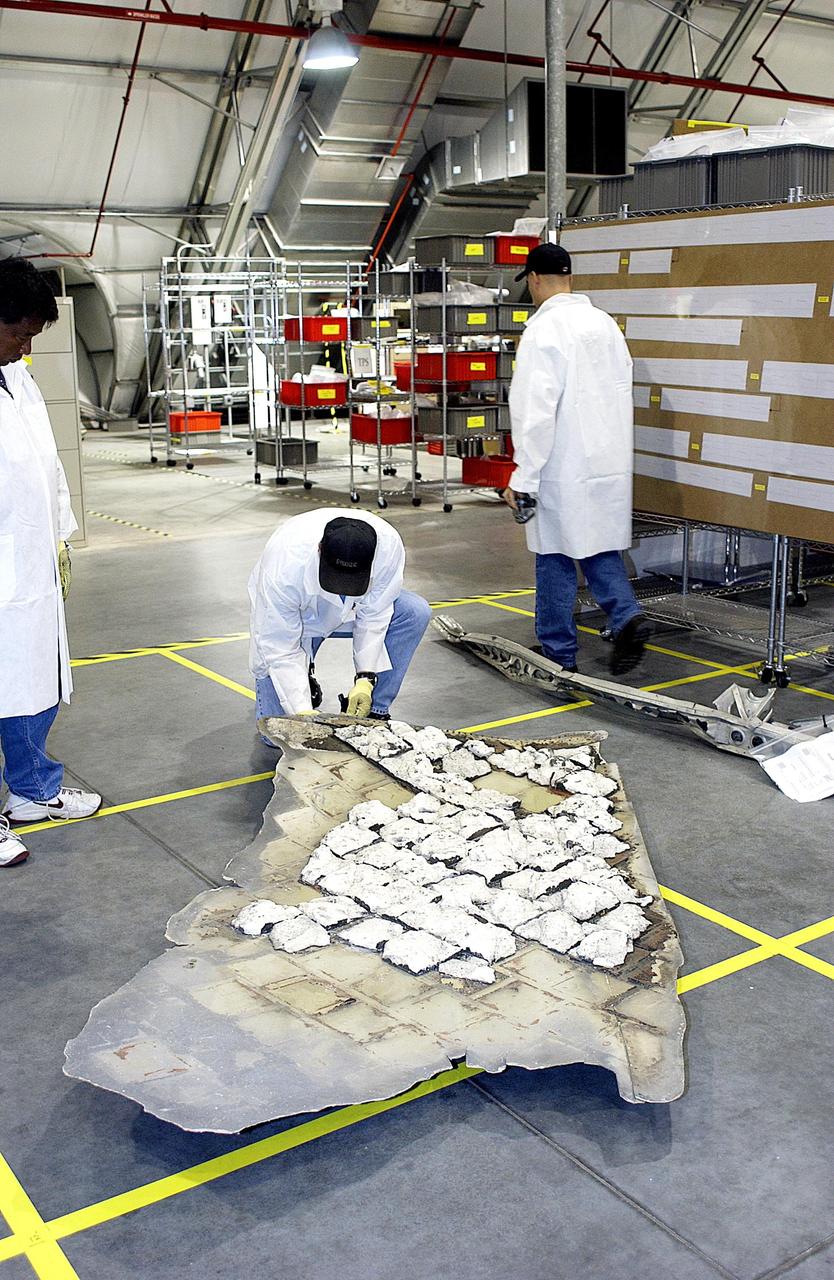 KENNEDY SPACE CENTER, FLA. -  Members of the Columbia Reconstruction Project Team place part of the final shipment of debris on the floor grid of the RLV Hangar. The recovery efforts have been concluded in East Texas.  Prior to this final shipment, the total number of items at KSC is 82,567, weighing 84,800 pounds or 38 percent of the total dry weight of Columbia.  Of those items, 78,760 have been identified, with 753 placed on the left wing grid in the RLV Hangar.