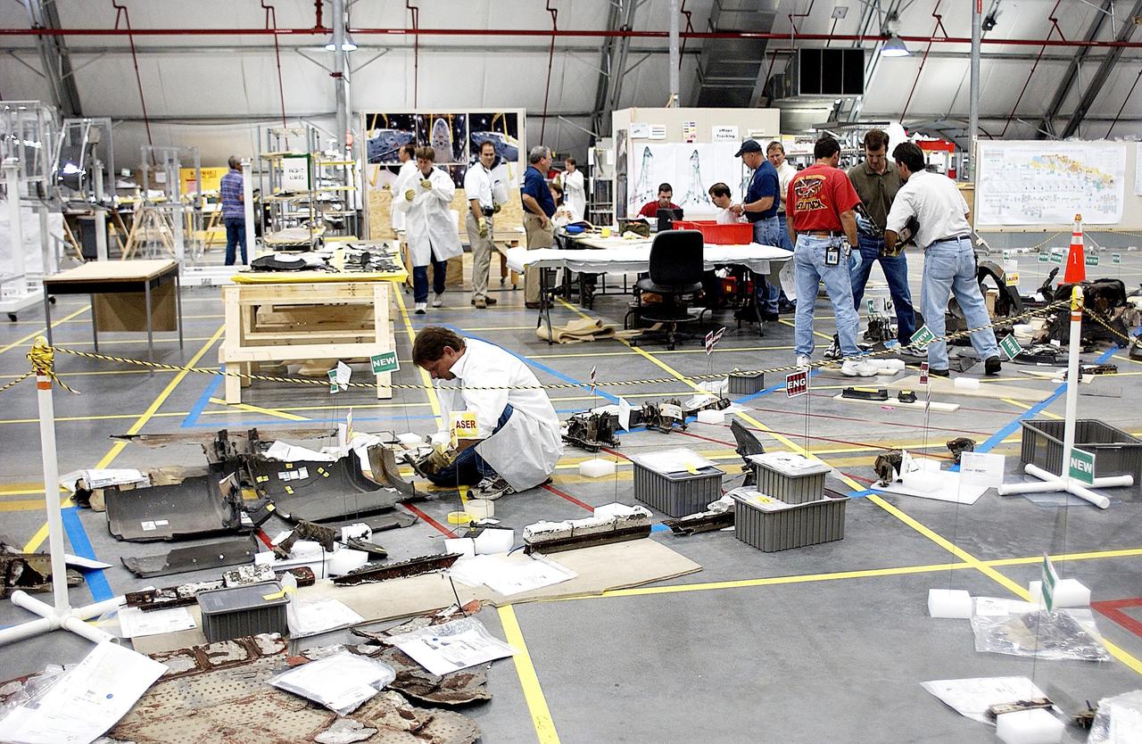 KENNEDY SPACE CENTER, FLA. - Members of the Columbia Reconstruction Project Team are scattered around the RLV Hangar as they examine various pieces of debris.  The final shipment of debris arrived on this date - recovery efforts have been concluded in East Texas.  Prior to this final shipment, the total number of items at KSC is 82,567, weighing 84,800 pounds or 38 percent of the total dry weight of Columbia.  Of those items, 78,760 have been identified, with 753 placed on the left wing grid in the RLV Hangar.