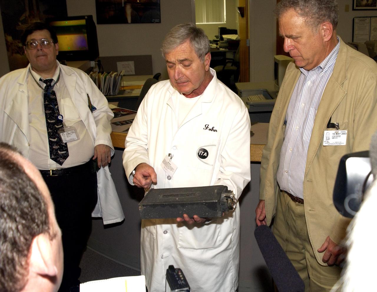 KENNEDY SPACE CENTER, FLA. -  John Cassanto (center), with Instrumentation Technology Associates, Inc., explains the use of the apparatus used for experiments on mission STS-107.   At left is Barry Perlman, with Pembroke Pines Middle School in Florida; at right is Lou Friedman, executive director of the Planetary Society. The box was part of the  Commercial ITA Biomedical Experiments payload on mission STS-107 that included the Growth of Bacterial Biofilm on Surfaces during Spaceflight (GOBBSS) experiment and crystals grown for cancer research.  The GOBBSS experiment was sponsored by the Planetary Society, with joint participation of an Israeli and a Palestinian student, and developed by the Israeli Aerospace Medical Institute and JSC Astrobiology Center.
