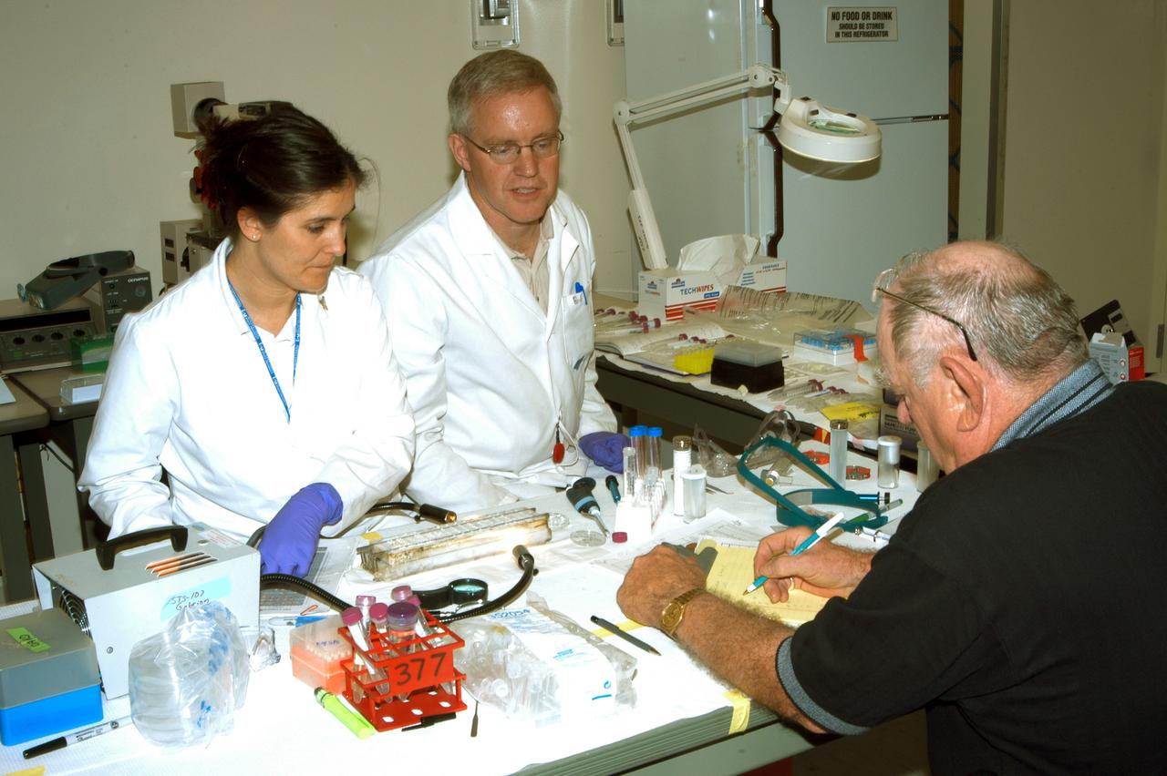 KENNEDY SPACE CENTER, FLA. - Valerie Cassanto and Bob McLean talk to a reporter about experiments found during the search for Columbia debris.  Cassanto is with Instrumentation Technology Associates Inc. and McLean is with the Southwest Texas State University. Included in the Commercial ITA Biomedical Experiments payload on mission STS-107 are urokinase cancer research, microencapsulation of drugs, the Growth of Bacterial Biofilm on Surfaces during Spaceflight (GOBBSS), and tin crystal formation.