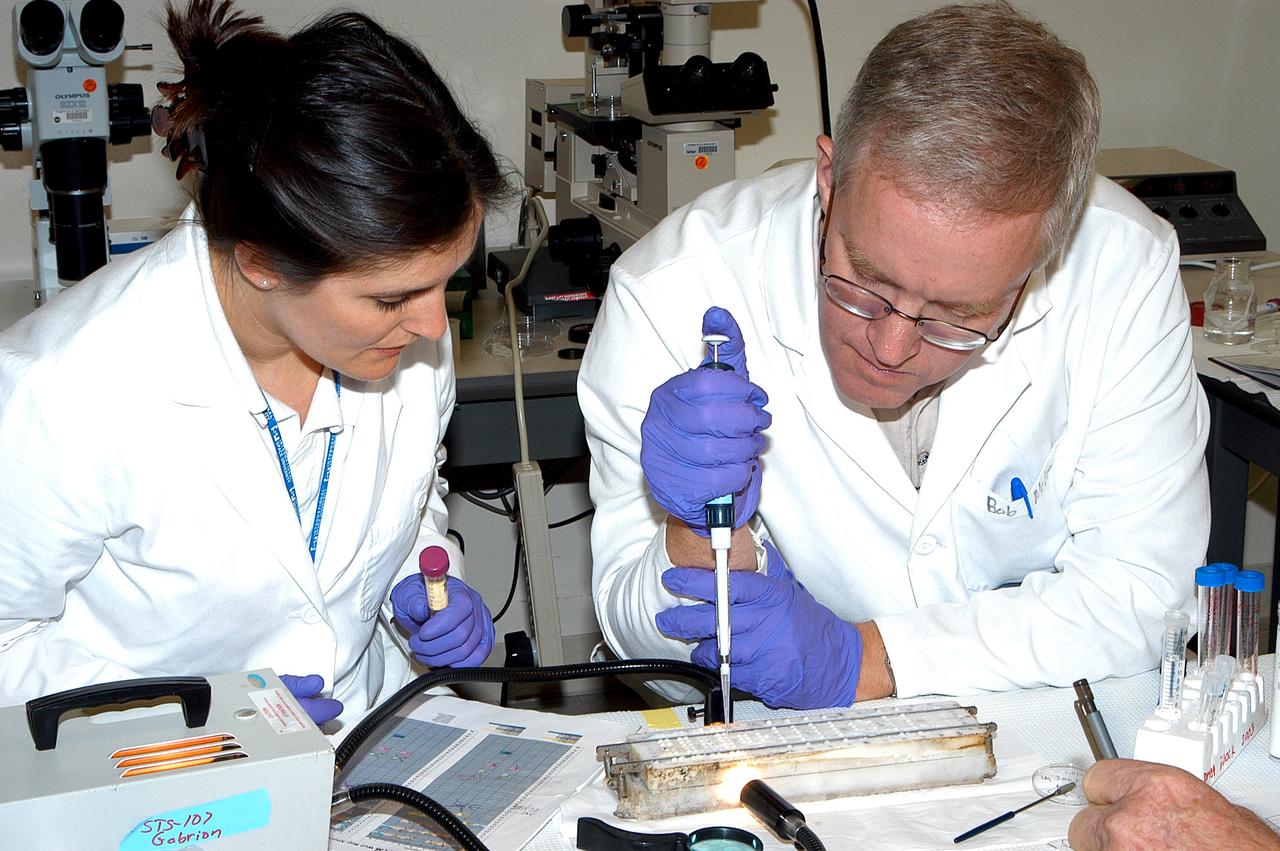 KENNEDY SPACE CENTER, FLA. - Valerie Cassanto, with Instrumentation Technology Associates, Inc., and Bob McLean, from the Southwest Texas State University, work on an experiment found during the search for Columbia debris.  Included in the Commercial ITA Biomedical Experiments payload on mission STS-107 are urokinase cancer research, microencapsulation of drugs, the Growth of Bacterial Biofilm on Surfaces during Spaceflight (GOBBSS), and tin crystal formation.
