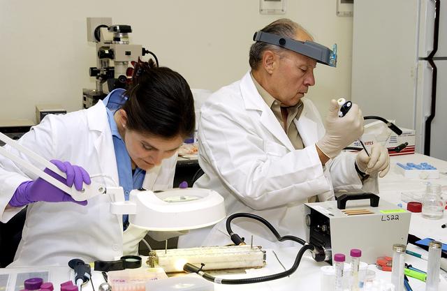 NASA image: KENNEDY SPACE CENTER, FLA. -  From left, Valerie Cassanto, Instrumentation Technology Associates, Inc., and Dr. Dennis Morrison, NASA Johnson Space Center, analyze one of the experiments carried on mission STS-107. Several experiments were found during the search for Columbia debris. Included in the Commercial ITA Biomedical Experiments payload on mission STS-107 are urokinase cancer research, microencapsulation of drugs, the Growth of Bacterial Biofilm on Surfaces during Spaceflight (GOBBSS), and tin crystal formation.