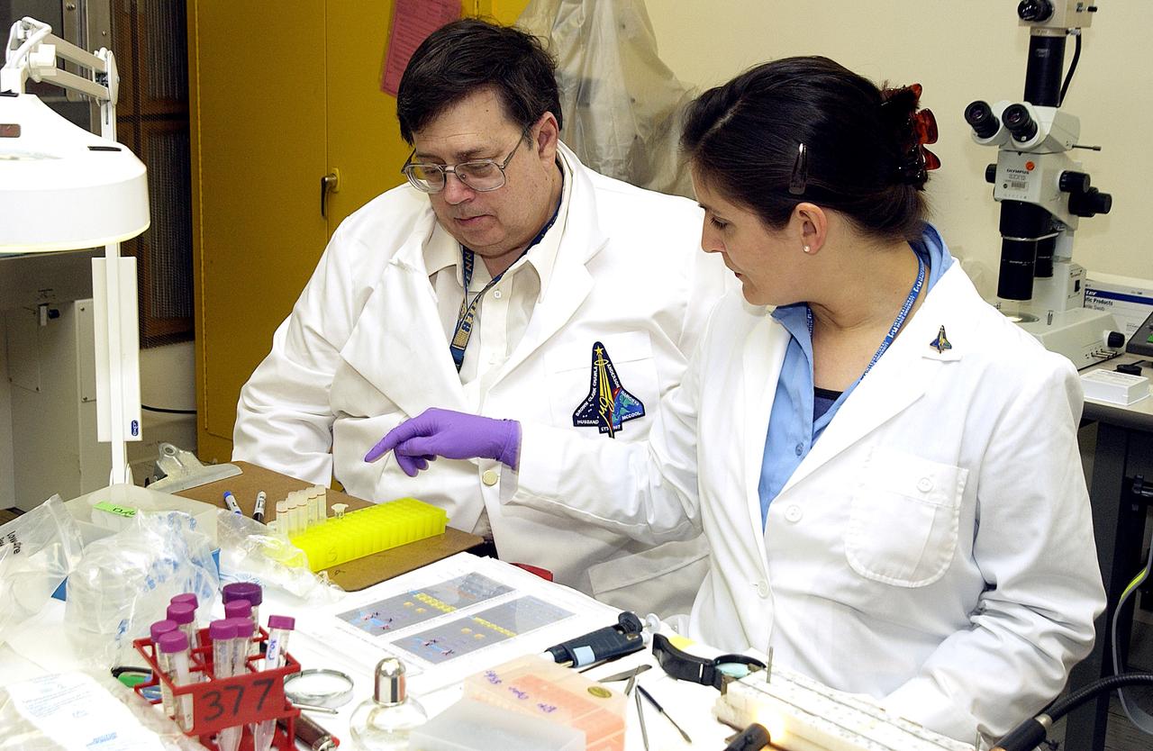 KENNEDY SPACE CENTER, FLA. -  From left, Barry Perlman, Pembroke Pines Charter Middle School in Florida, and Valerie Cassanto, Instrumentation Technology Associates, Inc., process one of the experiments carried on mission STS-107. Several experiments were found during the search for Columbia debris. Included in the Commercial ITA Biomedical Experiments payload on mission STS-107 are urokinase cancer research, microencapsulation of drugs, the Growth of Bacterial Biofilm on Surfaces during Spaceflight (GOBBSS), and tin crystal formation.  The latter was sponsored by the Pembroke Pines Charter Middle School.