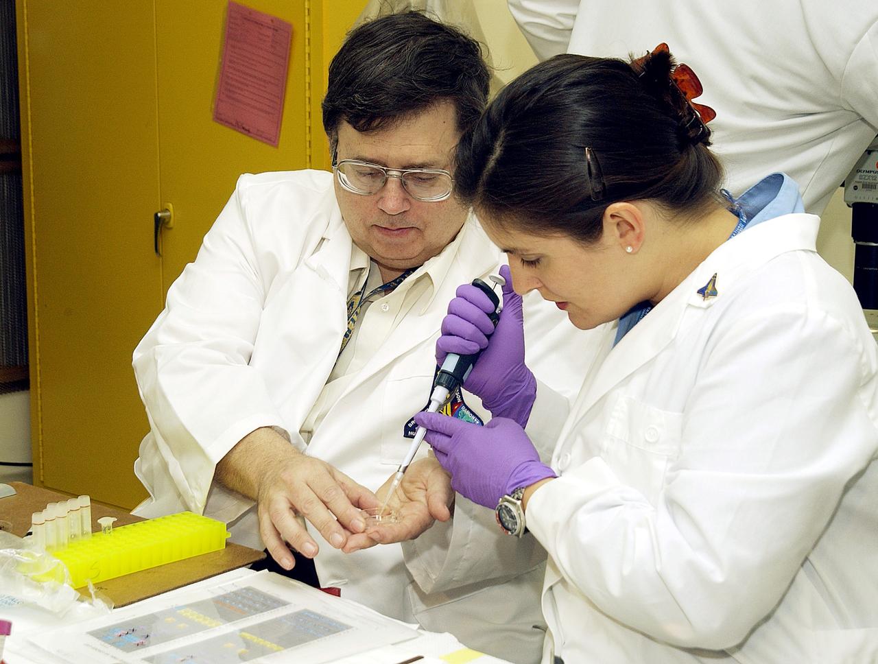 KENNEDY SPACE CENTER, FLA. -  From left, Barry Perlman, Pembroke Pines Charter Middle School in Florida, and Valerie Cassanto, Instrumentation Technology Associates, Inc., process one of the experiments carried on mission STS-107. Several experiments were found during the search for Columbia debris. Included in the Commercial ITA Biomedical Experiments payload on mission STS-107 are urokinase cancer research, microencapsulation of drugs, the Growth of Bacterial Biofilm on Surfaces during Spaceflight (GOBBSS), and tin crystal formation.  The latter was sponsored by the Pembroke Pines Charter Middle School.