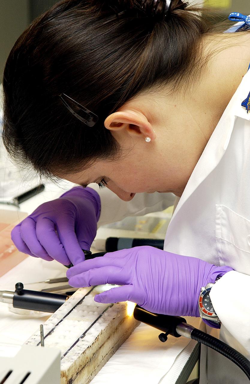 KENNEDY SPACE CENTER, FLA. -  Valerie Cassanto, Instrumentation Technology Associates, Inc., studies one of the experiments carried on mission STS-107. Several experiments were found during the search for Columbia debris. Included in the Commercial ITA Biomedical Experiments payload on mission STS-107 are urokinase cancer research, microencapsulation of drugs, the Growth of Bacterial Biofilm on Surfaces during Spaceflight (GOBBSS), and tin crystal formation.  The latter was sponsored by the Pembroke Pines Charter Middle School.