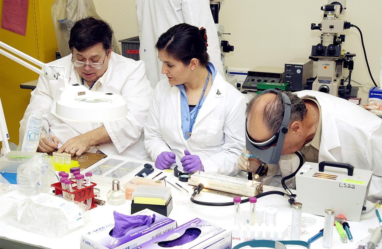 KENNEDY SPACE CENTER, FLA. -  From left, Barry Perlman, Pembroke Pines Charter Middle School in Florida; Valerie Cassanto, Instrumentation Technology Associates, Inc.; and Dr. Dennis Morrison, NASA Johnson Space Center, process one of the experiments carried on mission STS-107. Several experiments were found during the search for Columbia debris. Included in the Commercial ITA Biomedical Experiments payload on mission STS-107 are urokinase cancer research, microencapsulation of drugs, the Growth of Bacterial Biofilm on Surfaces during Spaceflight (GOBBSS), and tin crystal formation.  The latter was sponsored by the Pembroke Pines Charter Middle School.