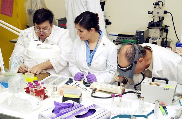NASA image: KENNEDY SPACE CENTER, FLA. -  From left, Barry Perlman, Pembroke Pines Charter Middle School in Florida; Valerie Cassanto, Instrumentation Technology Associates, Inc.; and Dr. Dennis Morrison, NASA Johnson Space Center, process one of the experiments carried on mission STS-107. Several experiments were found during the search for Columbia debris. Included in the Commercial ITA Biomedical Experiments payload on mission STS-107 are urokinase cancer research, microencapsulation of drugs, the Growth of Bacterial Biofilm on Surfaces during Spaceflight (GOBBSS), and tin crystal formation.  The latter was sponsored by the Pembroke Pines Charter Middle School.