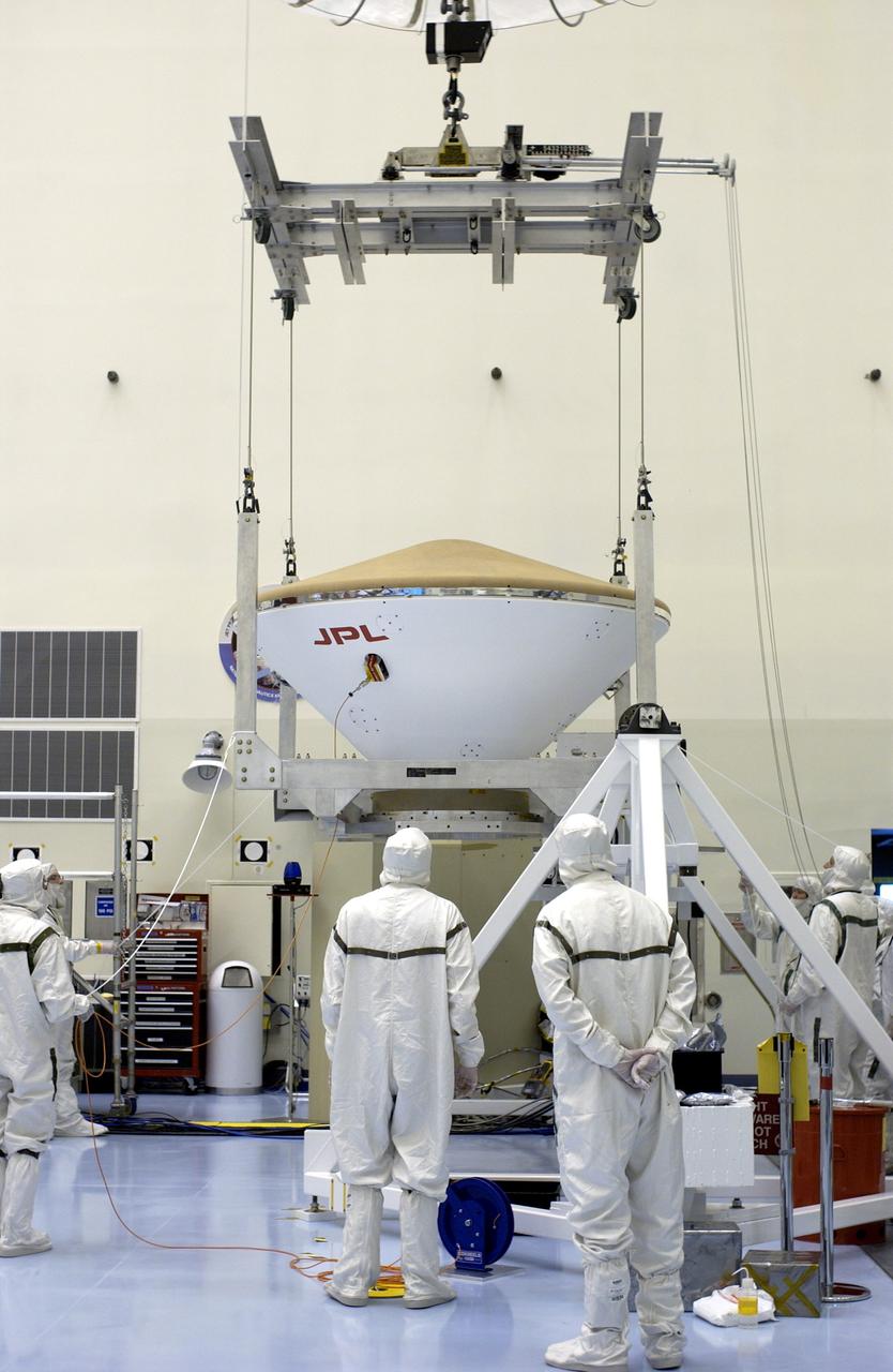 KENNEDY SPACE CENTER, FLA. - An overhead crane lifts the Mars Exploration Rover 2 (MER-2) entry vehicle from its stand to move it to a spin table for a dry-spin test.  The MER Mission consists of two identical rovers designed to cover roughly 110 yards each Martian day over various terrain. Each rover will carry five scientific instruments that will allow it to search for evidence of liquid water that may have been present in the planet's past.  Identical to each other, the rovers will land at different regions of Mars.  Launch for MER-2 (MER-A) is scheduled for June 5.