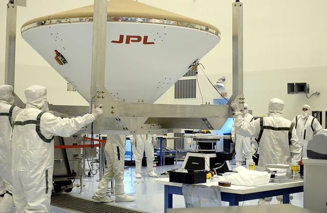 NASA image: KENNEDY SPACE CENTER, FLA. - Workers in the Payload Hazardous Servicing Facility help guide the Mars Exploration Rover 2 (MER-2) entry vehicle toward a spin table for a dry-spin test.  The MER Mission consists of two identical rovers designed to cover roughly 110 yards each Martian day over various terrain. Each rover will carry five scientific instruments that will allow it to search for evidence of liquid water that may have been present in the planet's past.  Identical to each other, the rovers will land at different regions of Mars.  Launch for MER-2 (MER-A) is scheduled for June 5.