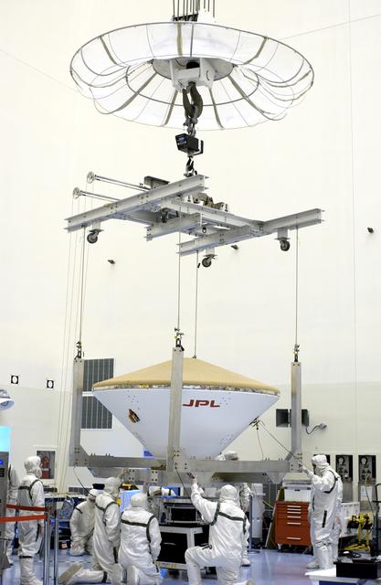 NASA image: KENNEDY SPACE CENTER, FLA. -  With help from workers, the overhead crane lowers the Mars Exploration Rover 2 (MER-2) entry vehicle onto a spin table for a dry-spin test.  The MER Mission consists of two identical rovers designed to cover roughly 110 yards each Martian day over various terrain. Each rover will carry five scientific instruments that will allow it to search for evidence of liquid water that may have been present in the planet's past.  Identical to each other, the rovers will land at different regions of Mars.  Launch for MER-2 (MER-A) is scheduled for June 5.