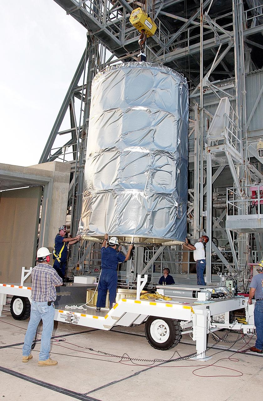 KENNEDY SPACE CENTER, FLA. - On Launch Complex 17-B, Cape Canaveral Air Force Station, the Space Infrared Telescope Facility (SIRTF) observatory is lowered onto a transporter to be taken back to NASA Spacecraft Hangar AE. SIRTF will remain in the clean room at Hangar AE until it returns to the pad in early August.