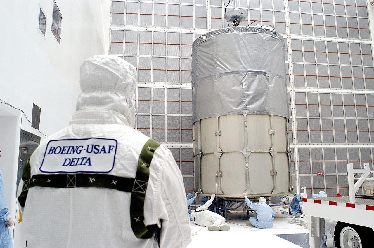 KENNEDY SPACE CENTER, FLA. -  Workers in NASA Spacecraft Hangar AE prepare to remove the canister from around the Space Infrared Telescope Facility (SIRTF), which has been returned to the hangar from the launch pad.   SIRTF will remain in the clean room until it returns to the pad in early August. One of NASA's largest infrared telescopes to be launched, SIRTF will obtain images and spectra by detecting the infrared energy, or heat, radiated by objects in space.