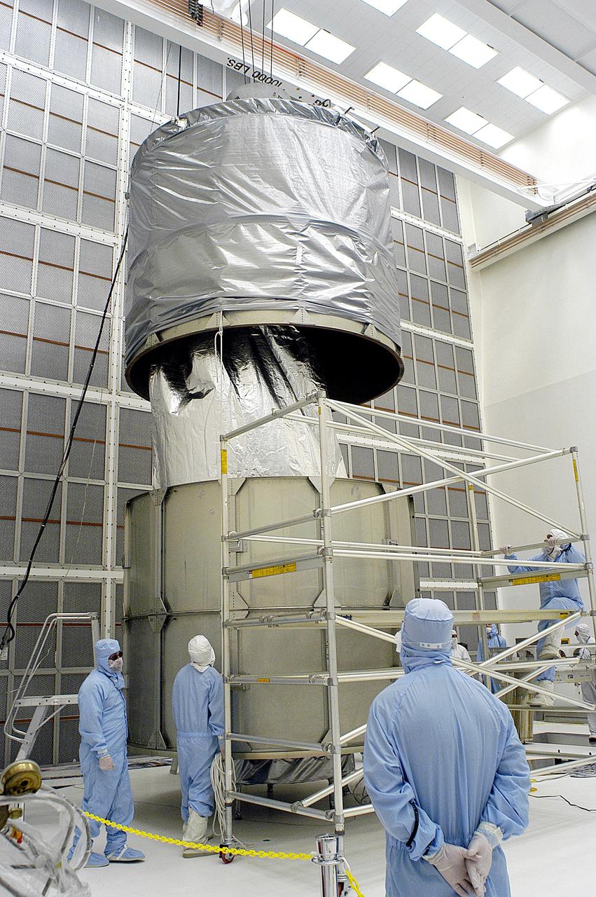 KENNEDY SPACE CENTER, FLA. -  Workers in NASA Spacecraft Hangar AE remove a portion of a transportation canister from around the Space Infrared Telescope Facility (SIRTF), which has been returned to the hangar from the launch pad.   SIRTF will remain in the clean room until it returns to the pad in early August. One of NASA's largest infrared telescopes to be launched, SIRTF will obtain images and spectra by detecting the infrared energy, or heat, radiated by objects in space.