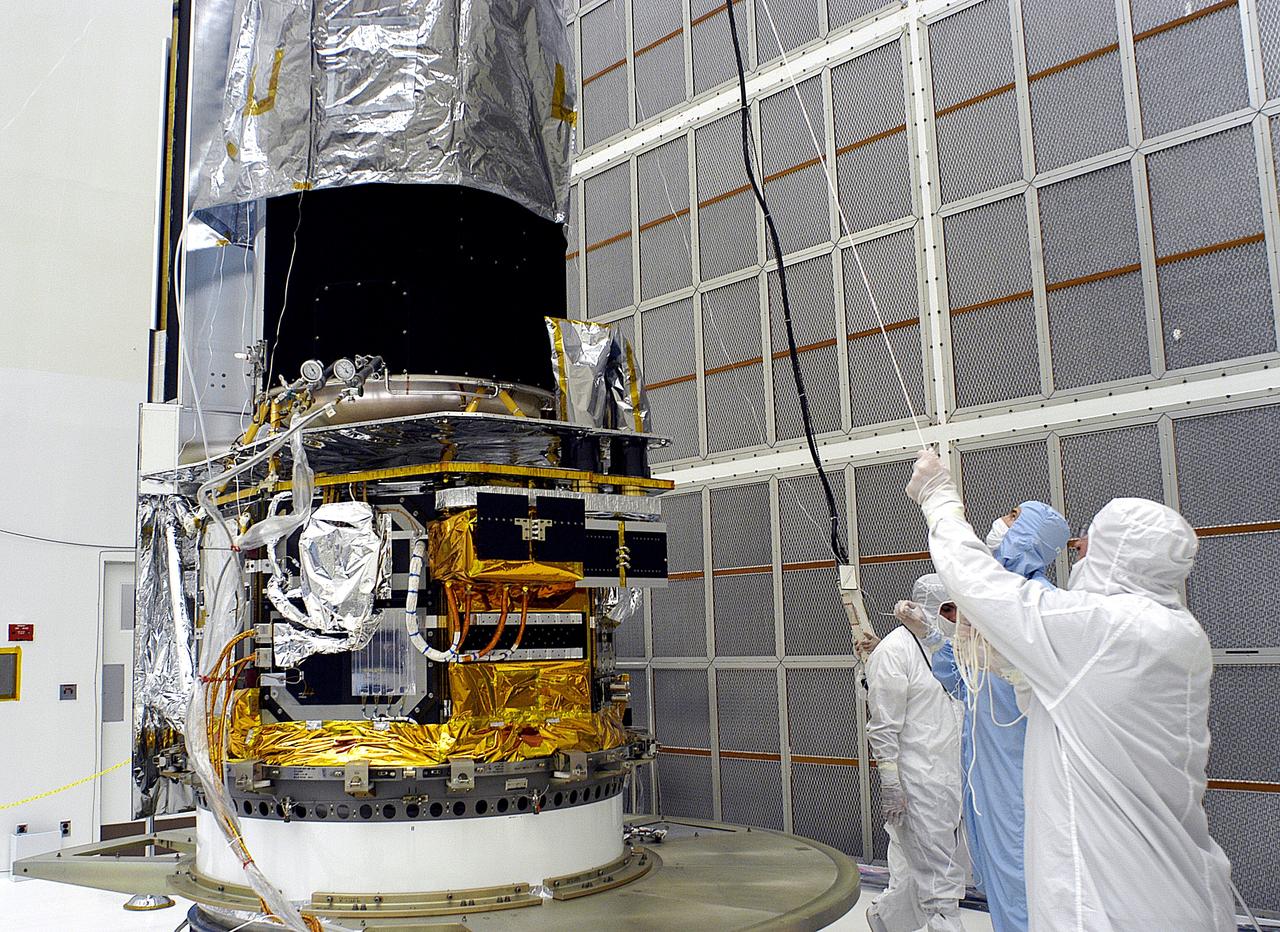 KENNEDY SPACE CENTER, FLA. -  Workers in NASA Spacecraft Hangar AE lift the protective cover from around the Space Infrared Telescope Facility (SIRTF), which has been returned to the hangar from the launch pad.   SIRTF will remain in the clean room until it returns to the pad in early August. One of NASA's largest infrared telescopes to be launched, SIRTF will obtain images and spectra by detecting the infrared energy, or heat, radiated by objects in space.