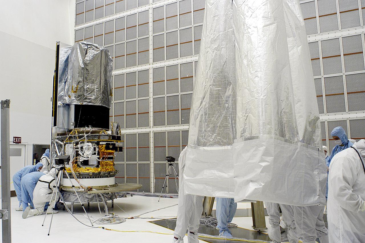 KENNEDY SPACE CENTER, FLA. -  Workers in NASA Spacecraft Hangar AE remove the protective cover from around the Space Infrared Telescope Facility (SIRTF), which has been returned to the hangar from the launch pad.   SIRTF will remain in the clean room until it returns to the pad in early August. One of NASA's largest infrared telescopes to be launched, SIRTF will obtain images and spectra by detecting the infrared energy, or heat, radiated by objects in space.