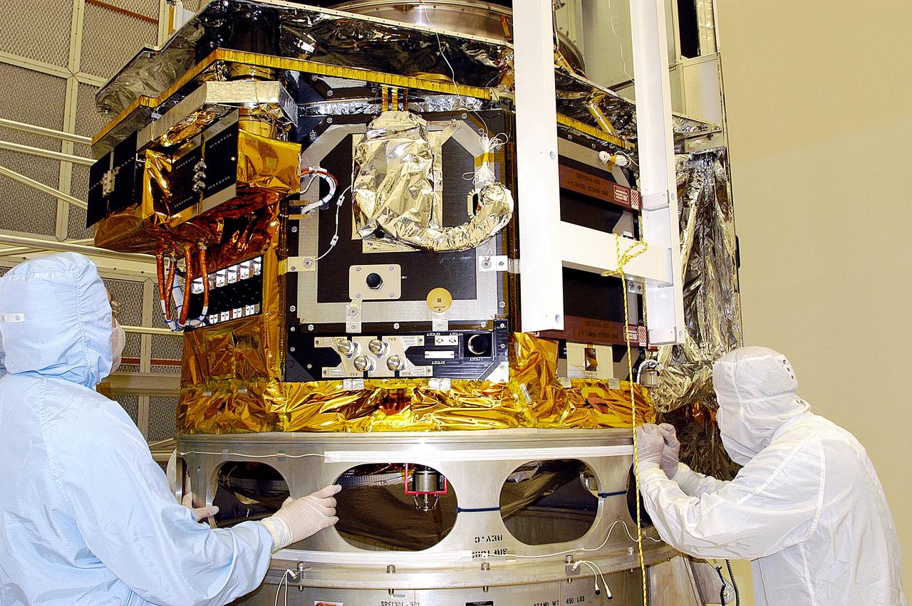 KENNEDY SPACE CENTER, FLA. -  Workers in NASA Spacecraft Hangar AE check the placement of the Space Infrared Telescope Facility (SIRTF), which has been returned to the hangar from the launch pad for further processing. SIRTF will remain in the clean room until it returns to the pad in early August. One of NASA's largest infrared telescopes to be launched, SIRTF will obtain images and spectra by detecting the infrared energy, or heat, radiated by objects in space.