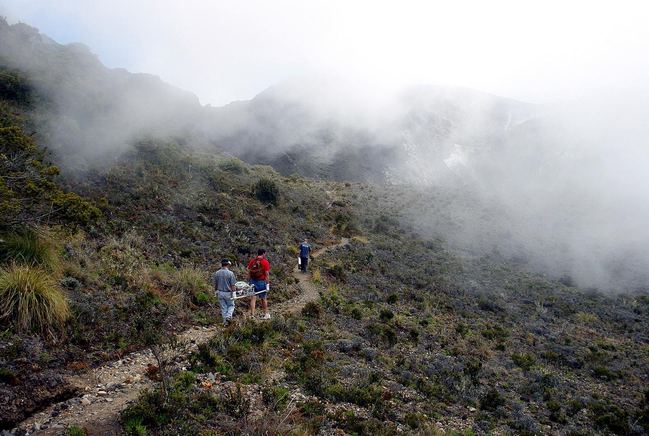 KENNEDY SPACE CENTER, FLA. -  Arturo Ramierez, Charles Curley and Duke Follistein, KSC and Costa Rican researchers, carry the hazardous gas detection system AVEMS to the central of the Turrialba volcano.  The Aircraft-based Volcanic Emission Mass Spectrometer determines the presence and concentration of various chemicals.  It is being tested in flights over the Turrialba volcano and in the crater, sampling and analyzing fresh volcanic gases in their natural chemical state.  The AVEMS system has been developed for use in the Space Shuttle program, to detect toxic gas leaks and emissions in the Shuttle’s aft compartment and the crew compartment.